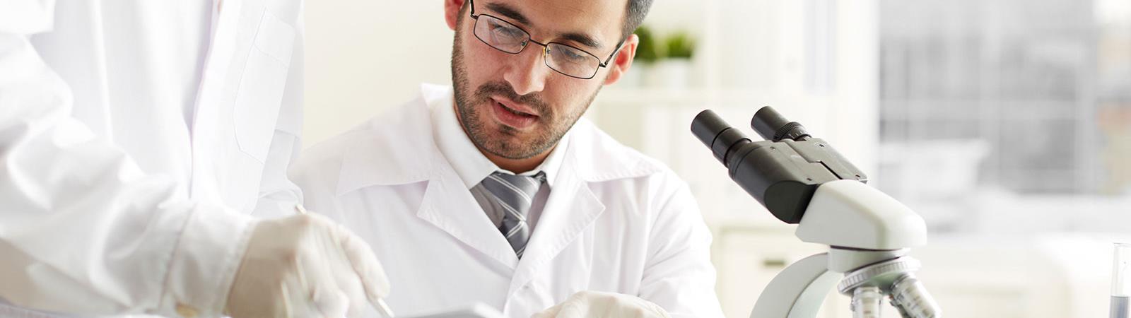 Two male scientist looking at a clipboard